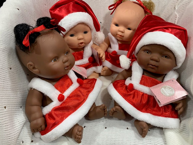 Four dolls dressed in red and white Christmas outfits on a textured surface.