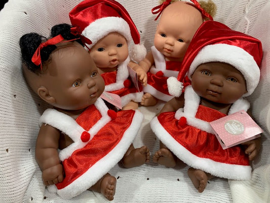 Four dolls dressed in red and white Christmas outfits on a textured surface.